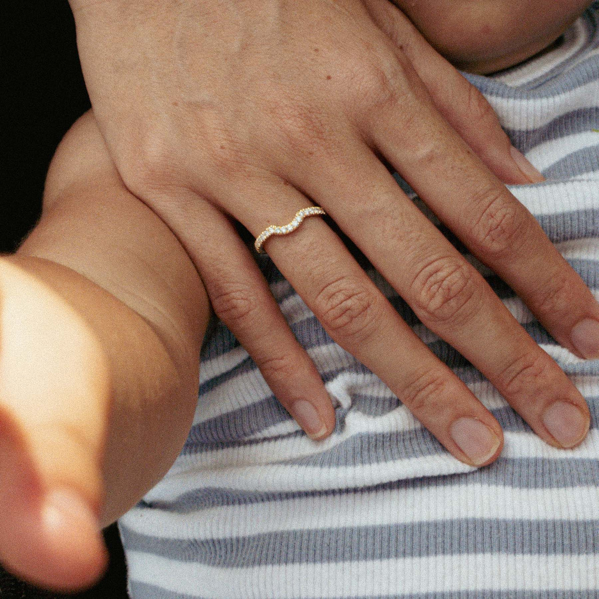 Her curved diamond band, her hand resting on their child
