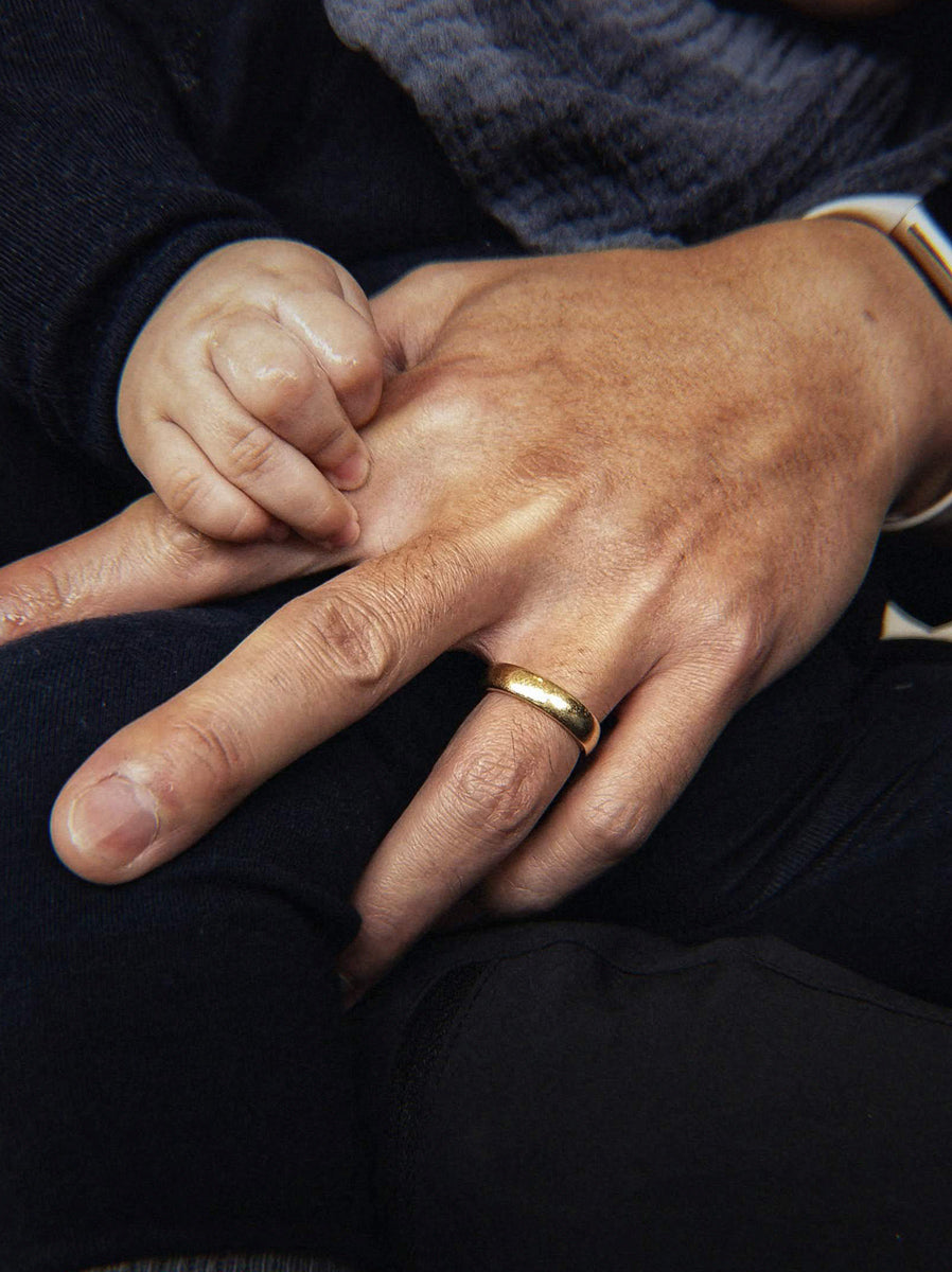 His plain gold band, their child holding his hand